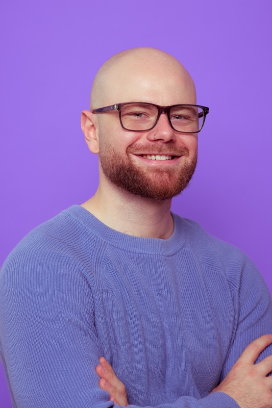 Rubin Koot stands with his arms crossed and smiles into the camera