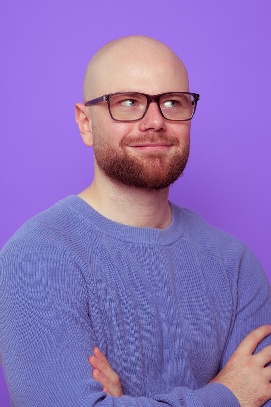 Rubin Koot staat met zijn armen over elkaar en kijkt glimlachend opzij