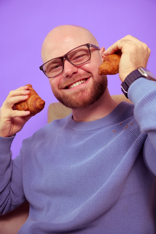 Rubin Koot grijnst breed met een croissant bij elk oor